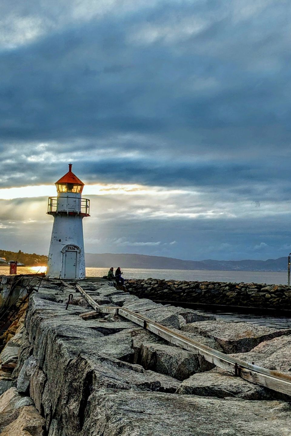 A lighthouse stands ready to guide mariners at the sun sets near Trondheim, Norway